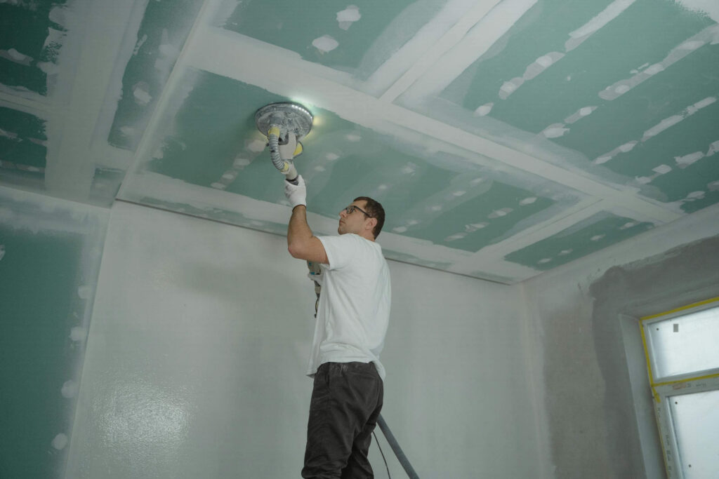 Contractor finishing and sanding a drywall ceiling during interior renovation in Lancaster.